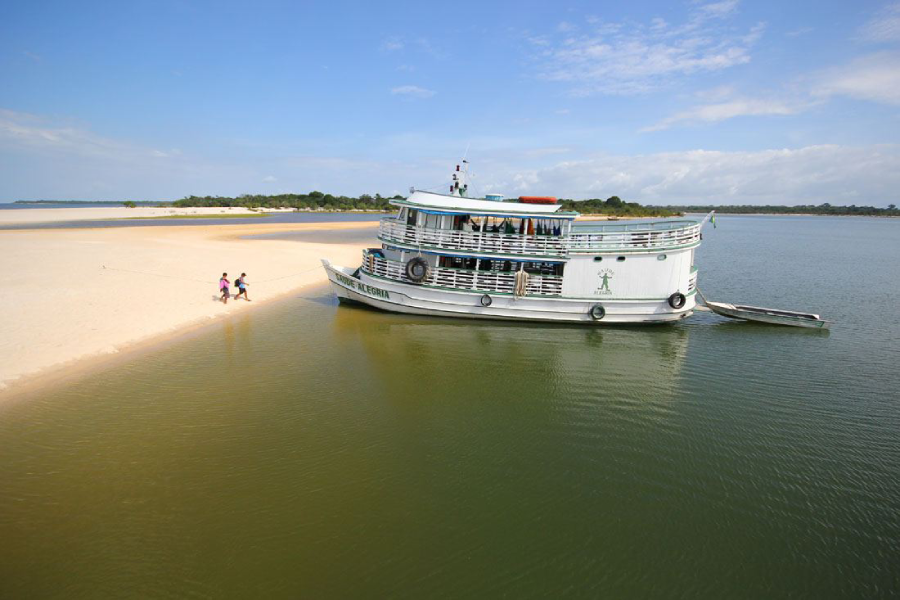 Barco branco ancorado ao lado de um banco de areia no rio