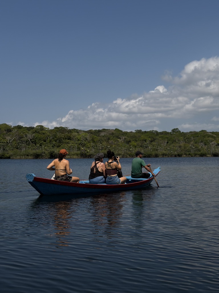Grupo de visitantes em uma canoa azul no rio calmo