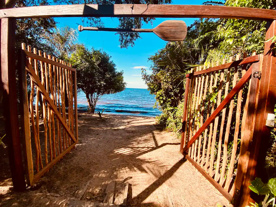Portão de madeira aberto para a praia do rio